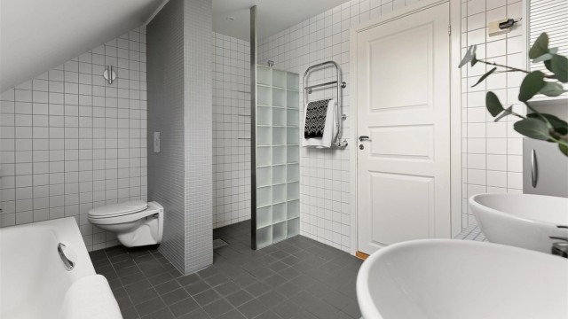 Badet har både badekar og en separat dusjnisje med vegg av glassbyggerstein.