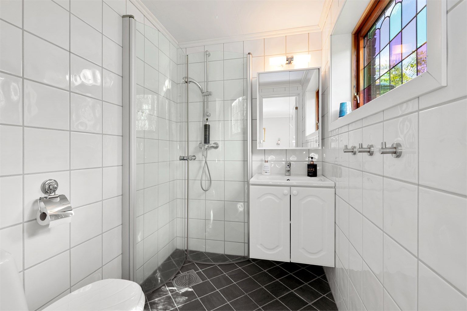 Flislagt bad fra 2015 med wc, innredning med servant, speil med overlys og dusjhjørne med foldbare glassvegger