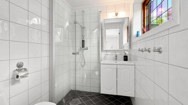 Flislagt bad fra 2015 med wc, innredning med servant, speil med overlys og dusjhjørne med foldbare glassvegger