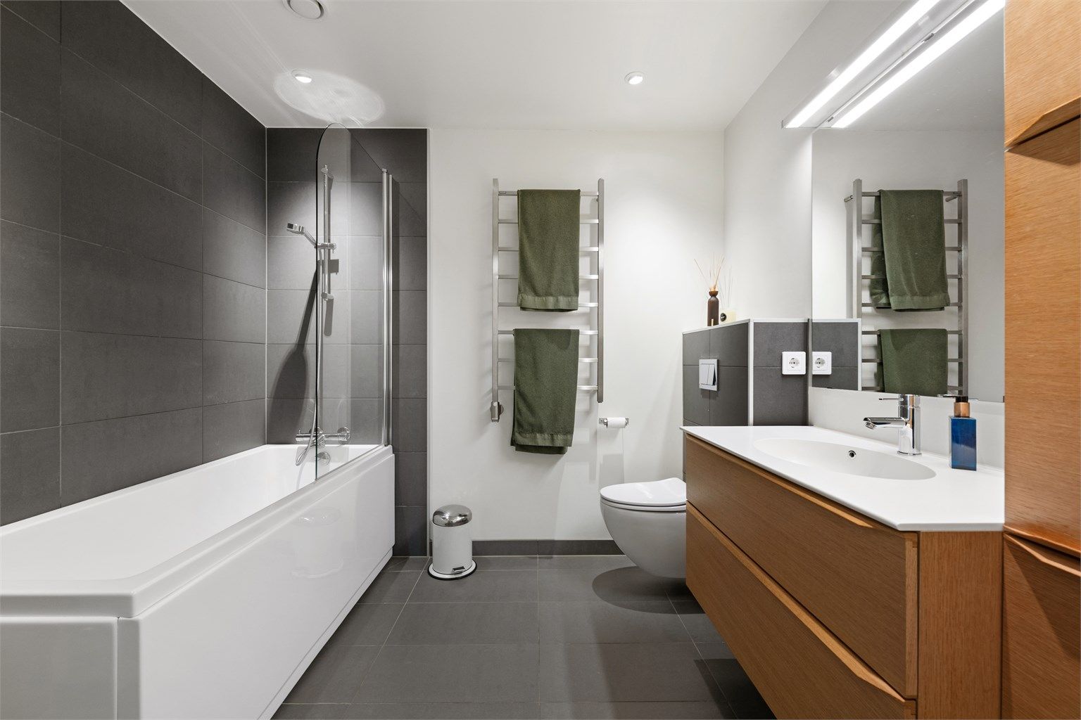 Badet i underetasjen er utstyrt med badekar, vegghengt toalett og servantinnredning