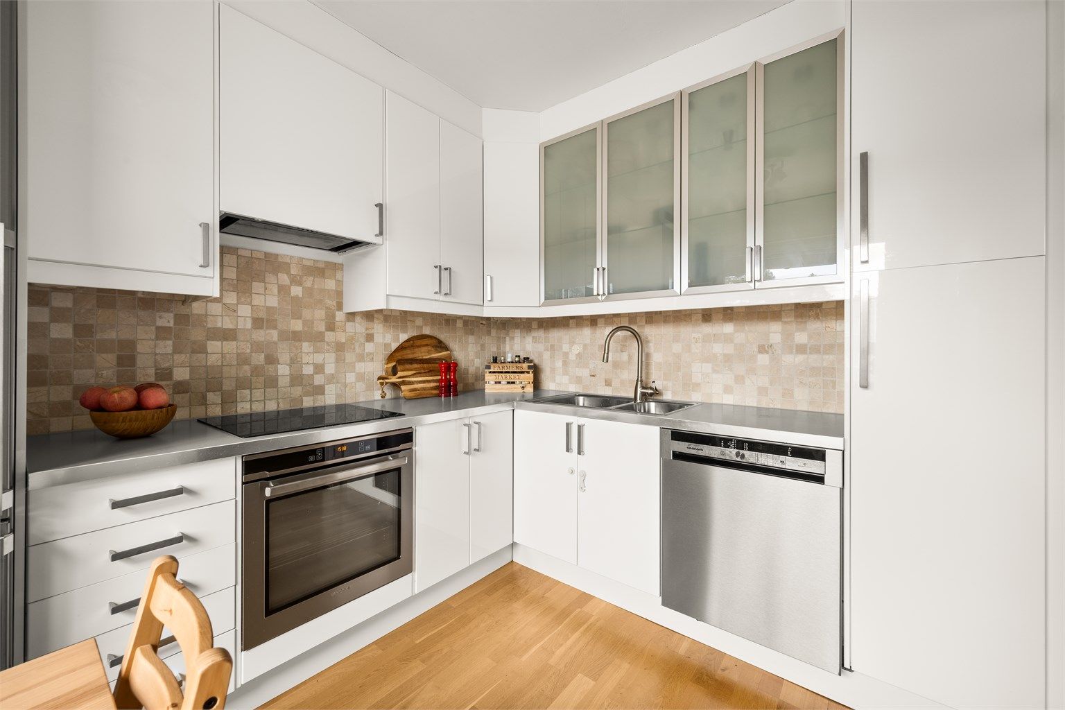 Kjøkkenet har slette, hvite fronter og laminat benkeplate. Fliser på vegg over kjøkkenbenk.