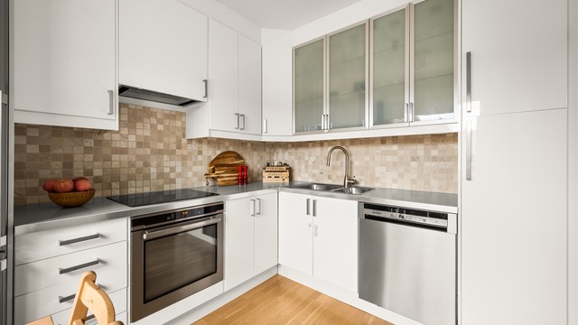 Kjøkkenet har slette, hvite fronter og laminat benkeplate. Fliser på vegg over kjøkkenbenk.