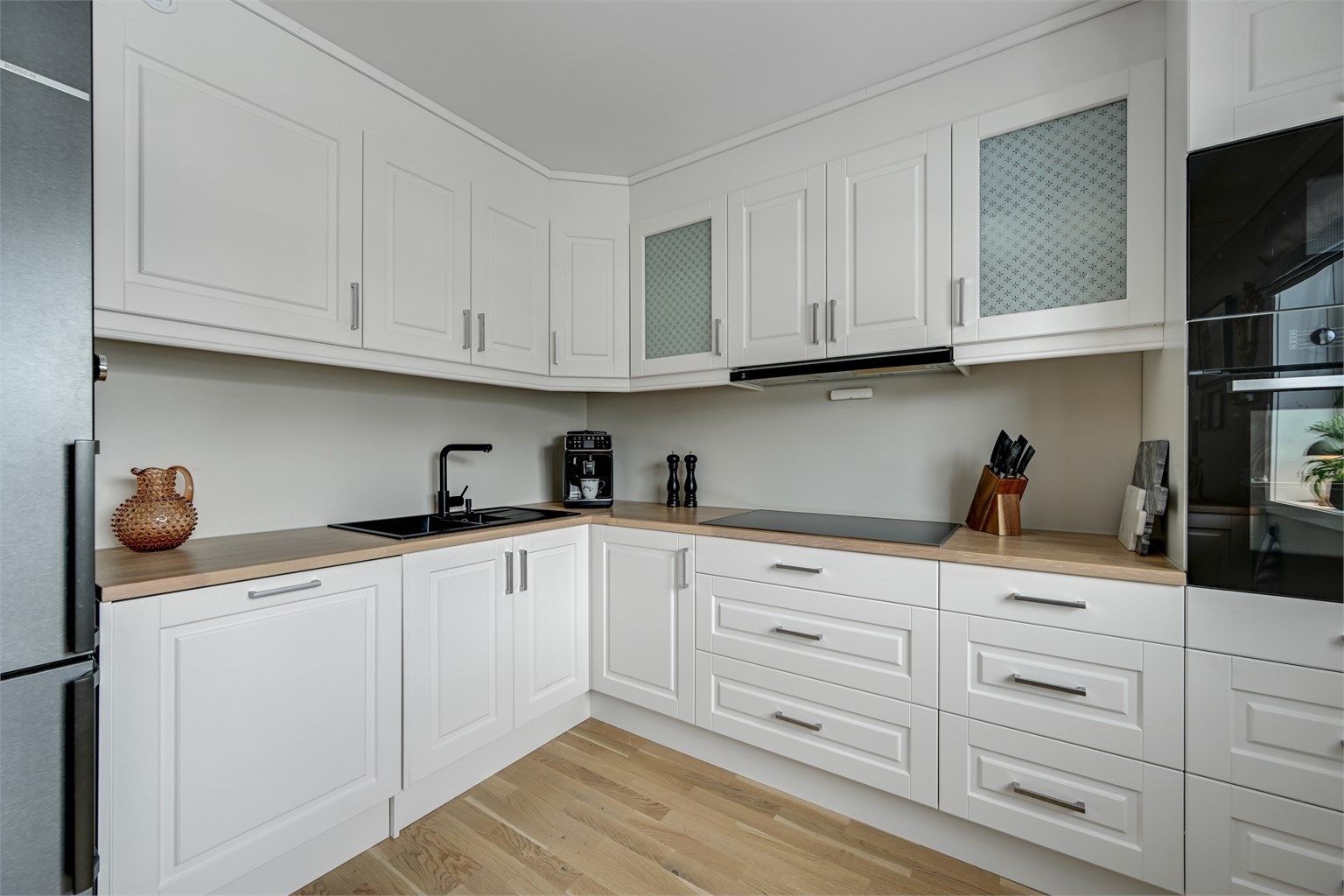 Integrerte hvitevarer som oppvaskmaskin, induksjonstopp, stekeovn og mikrobølgeovn gir et ryddig uttrykk, og det er avsatt plass til frittstående kjøleskap. Hvitevarene er fra merket Miele.