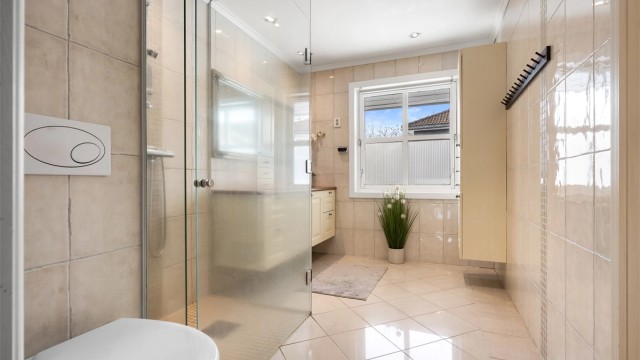 Baderom fra vurdert til å være fra 2005 (datostemplet avløpsrør i sluk). Det er flislagt gulv med varme og flislagte vegger, himling med malt slett flate og downlights, og vegghengt servantskap med profilerte fronter.