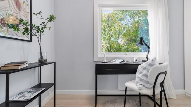 Arbeidsplass plassert foran vinduet med utsikt mot hagen utenfor.
