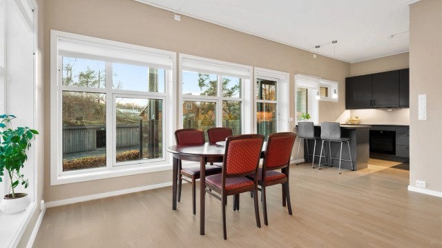 Lys og koselig stue med åpen kjøkkenløsning - store vinduer gir rikelig med dagslys.