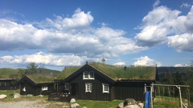 Hytta glir fint inn i terrenget med sin tradisjonelle arkitektur og torvtak.