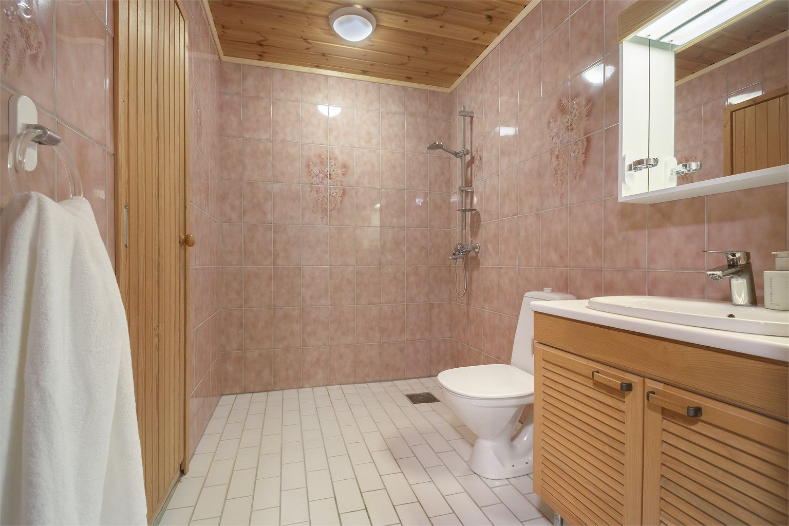Badet i underetasje er flislagt og utstyrt med gulvstående toalett, servantinnredning med speilskap og dusjsone med god plass til badekar.