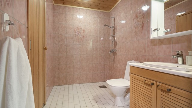 Badet i underetasje er flislagt og utstyrt med gulvstående toalett, servantinnredning med speilskap og dusjsone med god plass til badekar.