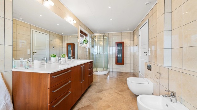 Badet har innebygd boblebadekar med badekarsarmatur, bide, dusjkabinett og vegghengt toalett.