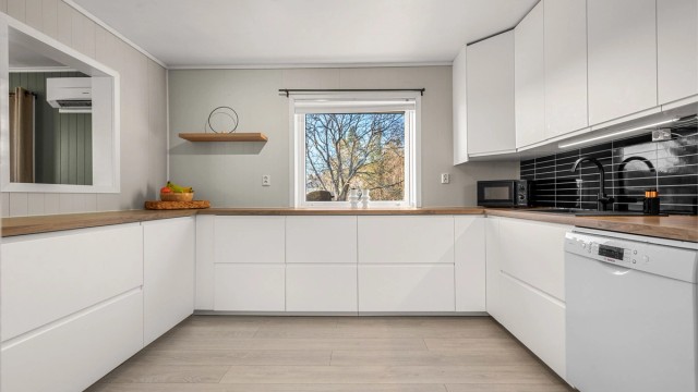 Moderne IKEA-kjøkken fra 2025 med lyse, glatte fronter og benkeplate i tre.