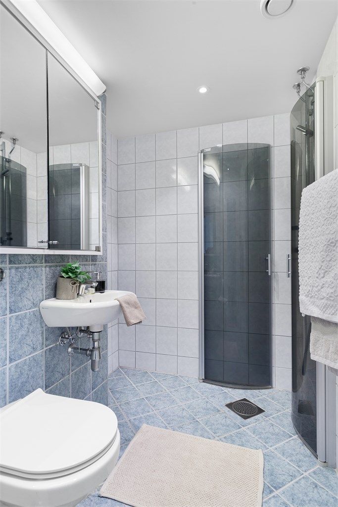 Speilskap med overlys over servant. Dusjhjørne med dører. Opplegg for vaskemaskin.