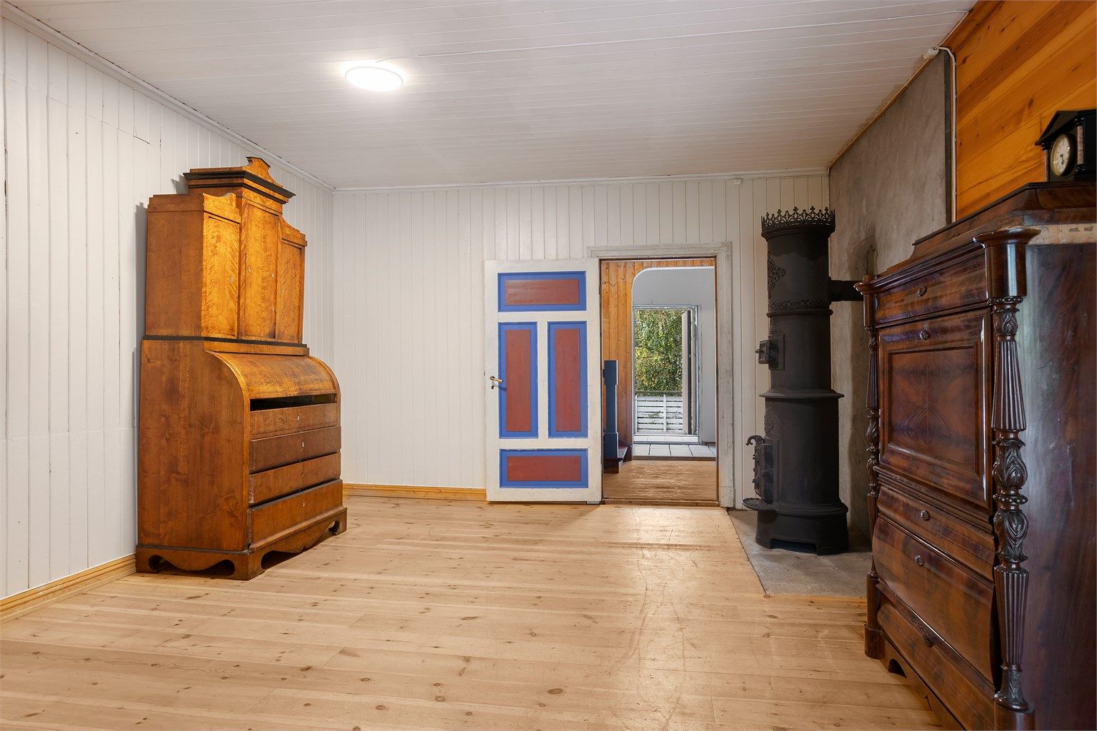 Stue med heltre gulv og klassisk peisovn for oppvarming.