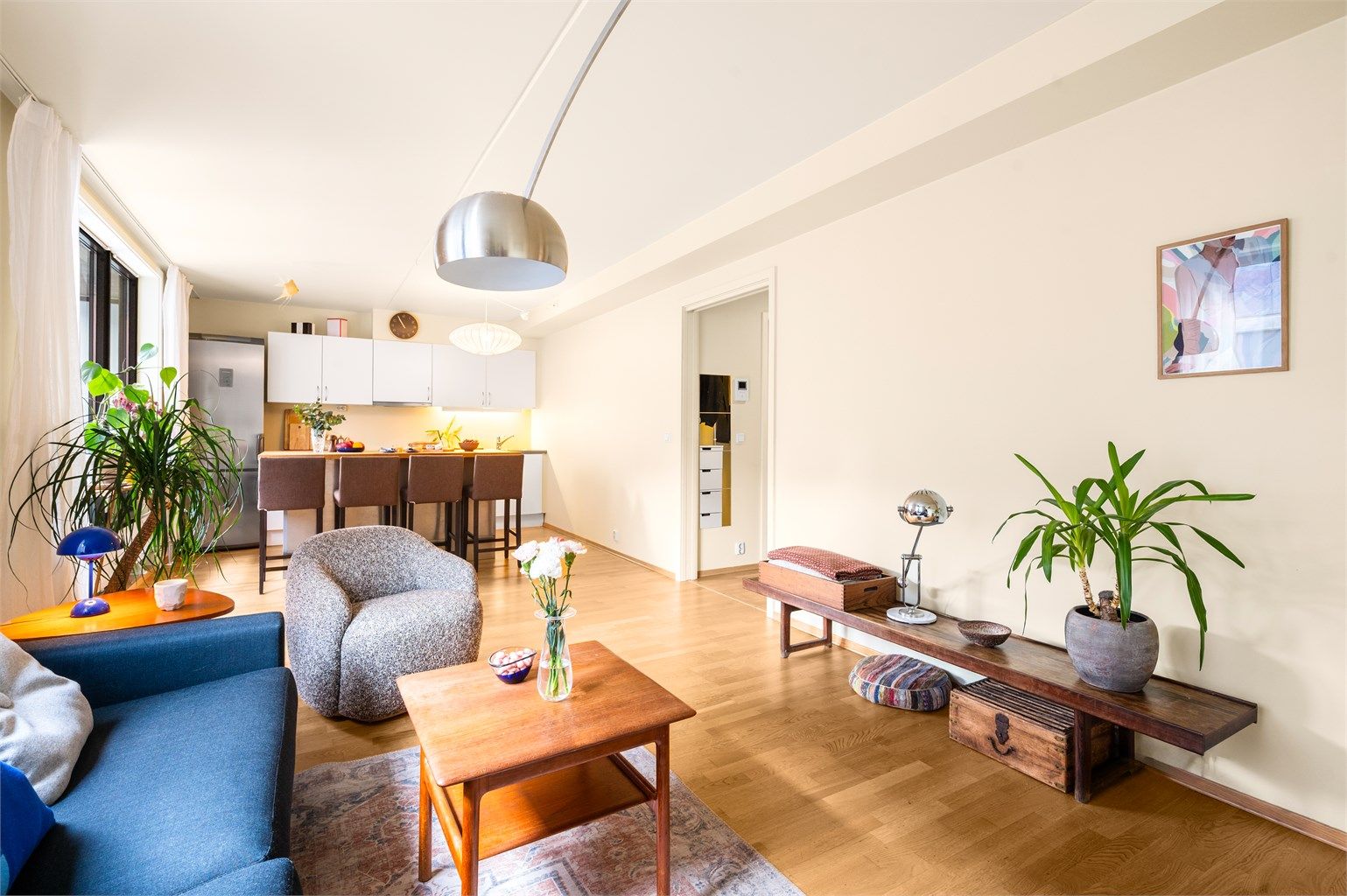 Stue med åpen kjøkkenløsning og praktisk kjøkkenøy med barstoler. 