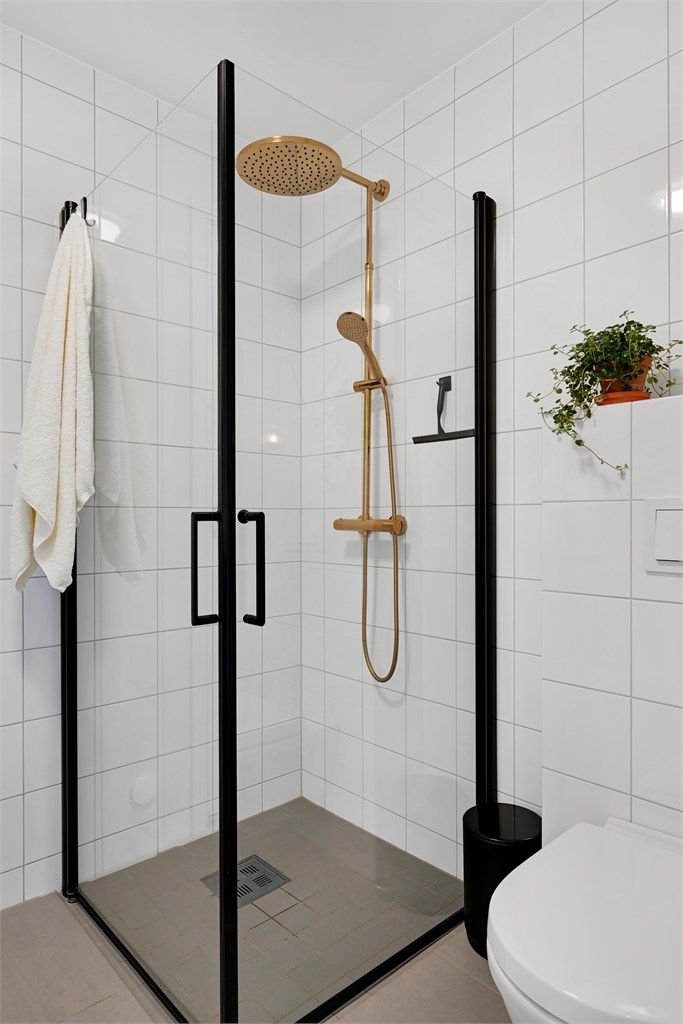 Dusjhjørne med innfellbare glassdører og stilrent blandebatteri i messing.