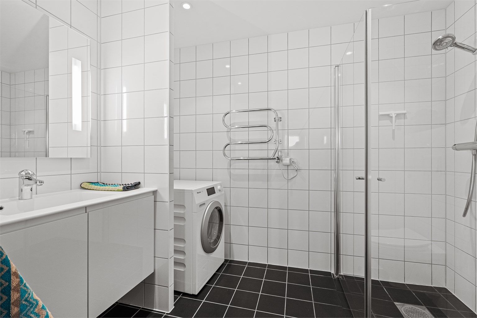 Fint helfliset bad av god størrelse med opplegg for vaskemaskin, samt plass til tørketrommel. Varme i gulv og servant med oppbevaring i skap. Stort speil på vegg. Håndkletørker på vegg.