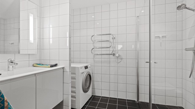 Fint helfliset bad av god størrelse med opplegg for vaskemaskin, samt plass til tørketrommel. Varme i gulv og servant med oppbevaring i skap. Stort speil på vegg. Håndkletørker på vegg.