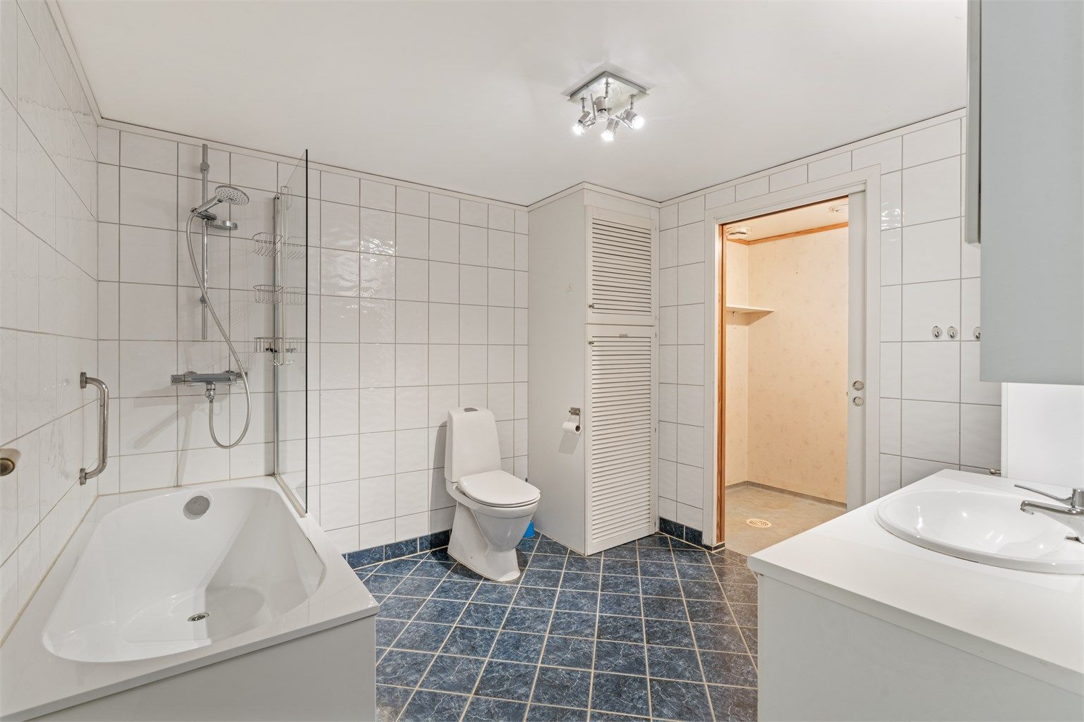 Romslig, helfliset bad med badekar, servantinnredning og toalett.