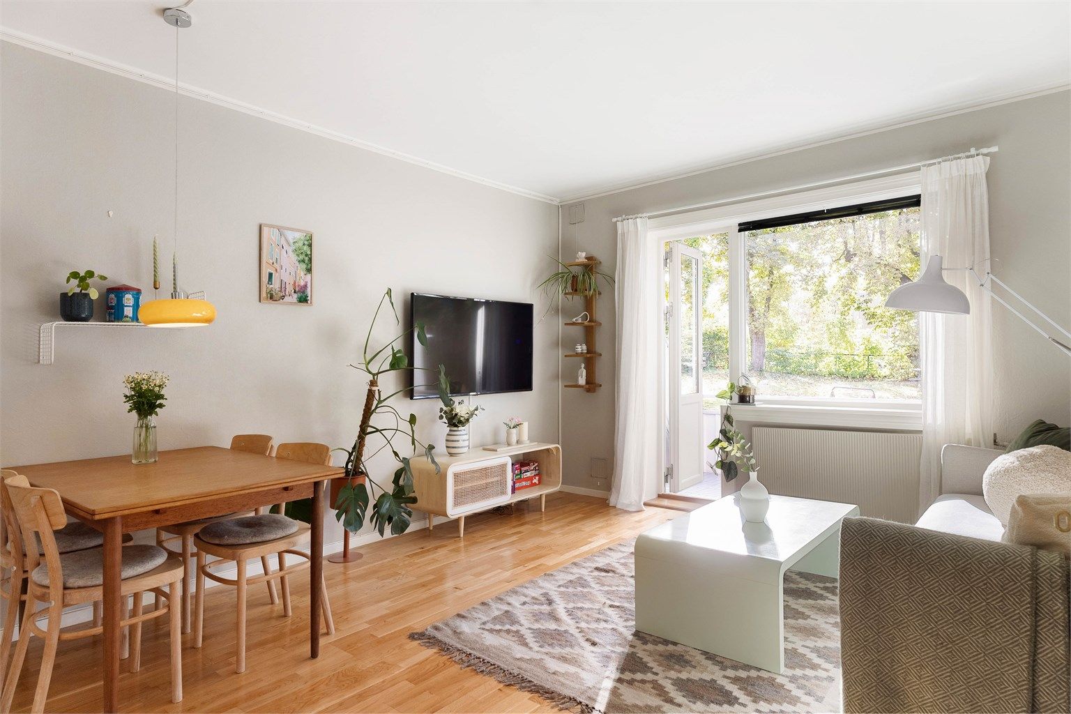 Stuen har god plass til både spisebord og sofagruppe, og den åpne løsningen mot kjøkkenet skaper et sosialt og hyggelig samlingspunkt.