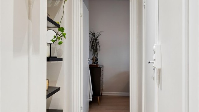 Lys fordelingsgang med åpne hylleplasser og slette veggflater.