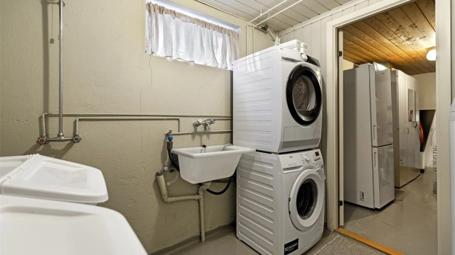 Praktisk vaskerom i kjelleren med dusj, utslagsvask og opplegg for vaskemaskin.