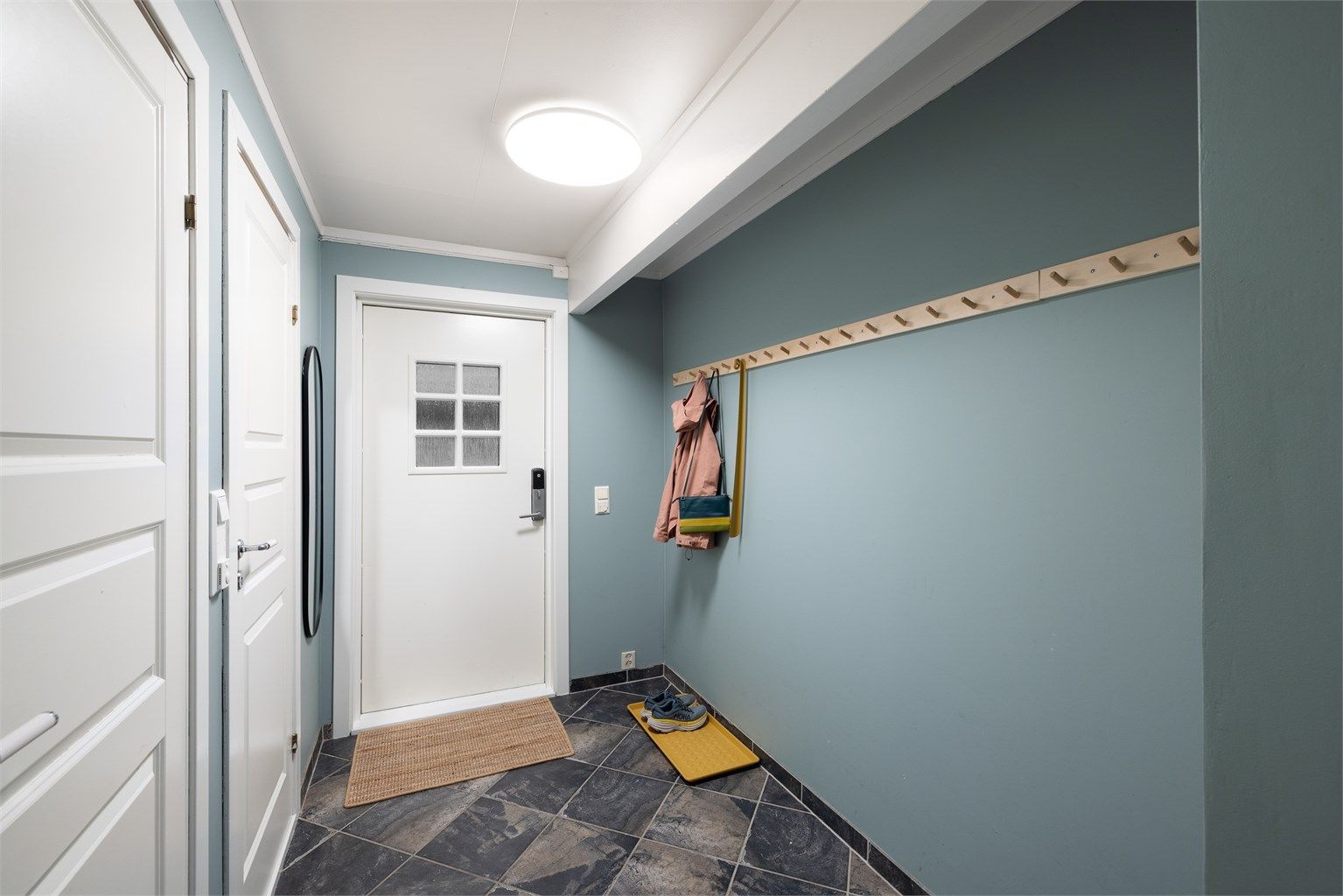 Velkommen inn i en romslig entré med god plass til oppbevaring av yttertøy. Det er montert kodelås på ytterdøren for en enklere og nøkkelfri hverdag.
