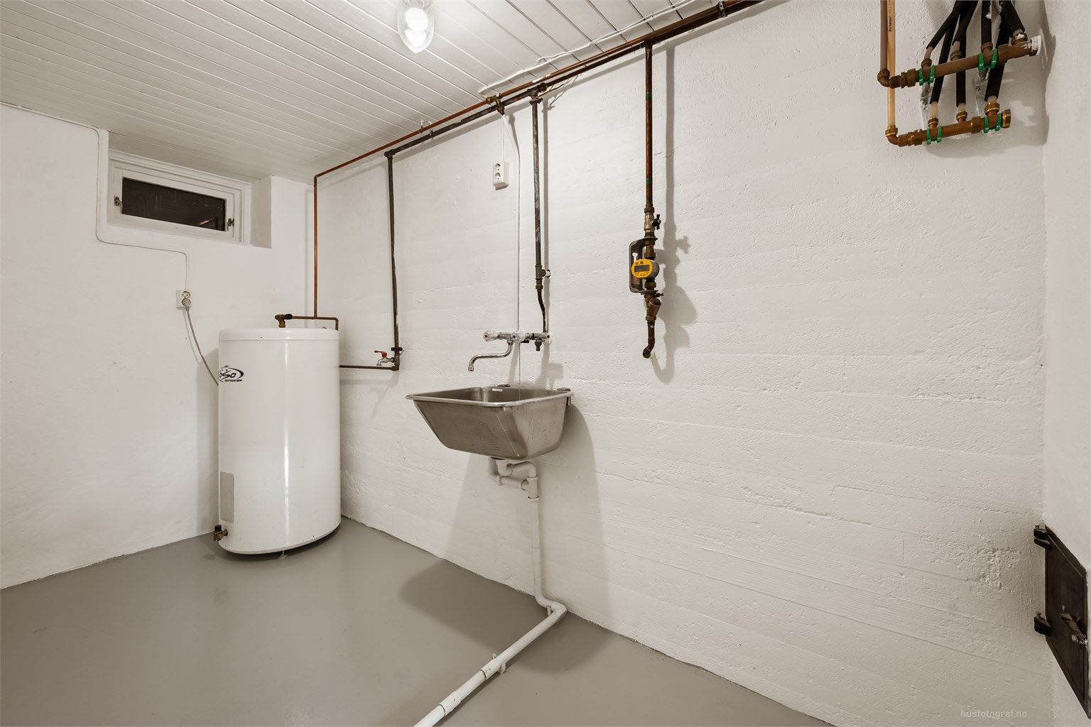 Praktisk vaskerom med utslagsvask, opplegg for vaskemaskin og en varmtvannsbereder på 198 liter.