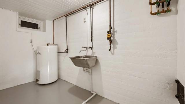 Praktisk vaskerom med utslagsvask, opplegg for vaskemaskin og en varmtvannsbereder på 198 liter.
