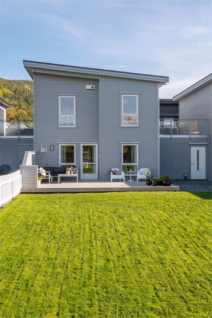 Flat og lettstelt plen inngjerdet med hvitt stakittgjerde, ideelt for lek og utendørsaktiviteter.
