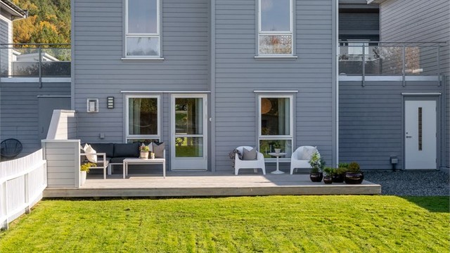 Flat og lettstelt plen inngjerdet med hvitt stakittgjerde, ideelt for lek og utendørsaktiviteter.