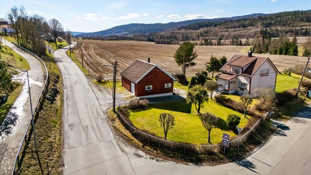 En klassisk enebolig fra 1936 med en stor, separat uthusbygning, beliggende på en tilnærmet flat tomt i landlige omgivelser.
Foto: Haiman Askari