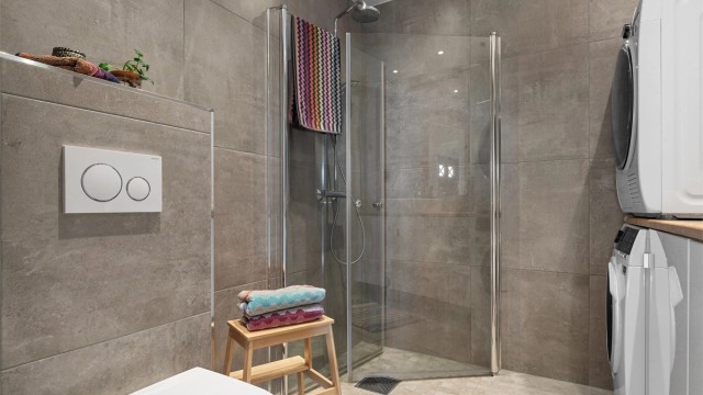 Badet er også innredet med vegghengt toalett og dusjhjørne med innfellbare glassvegger, hånd- og regnfallsdusj. Det er i tillegg opplegg til vaskemaskin.