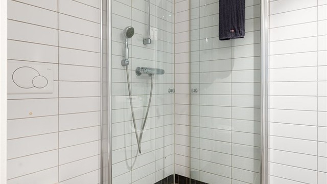 Dusjhjørne med svingbare glassdører og vegghengt toalett.