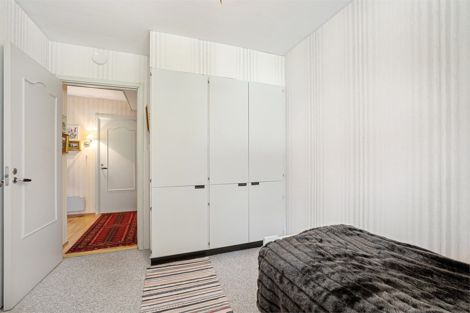 Lyst soverom med klesoppbevaring i garderobeskap.