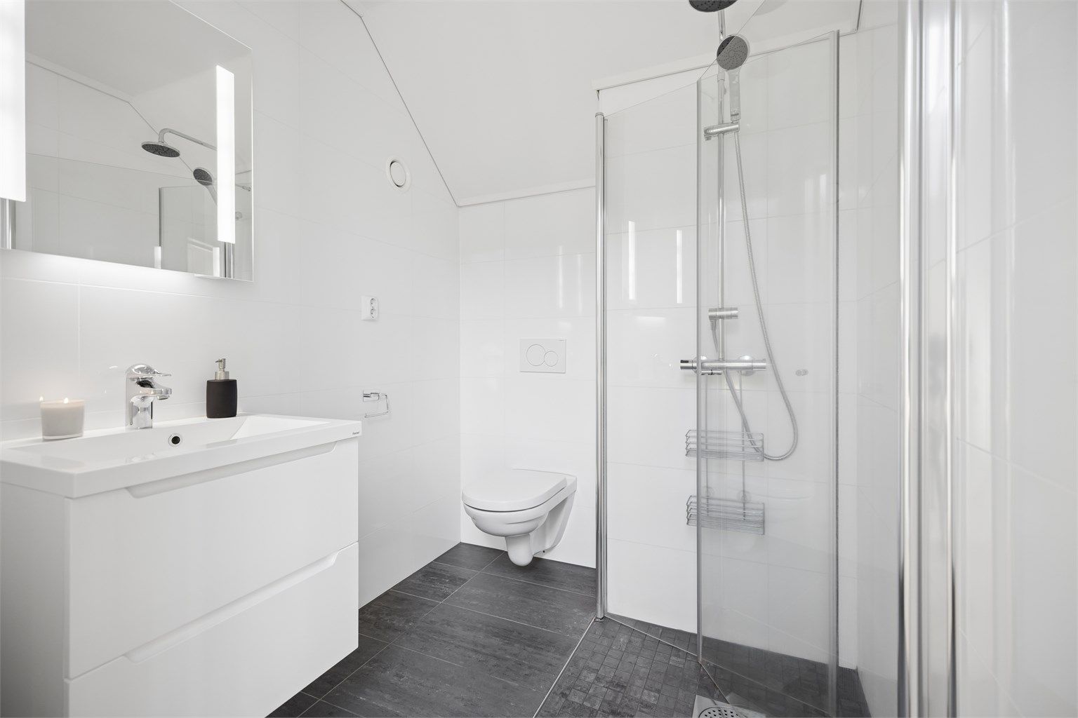 Badet i 3.etg har moderne lekre fliser, gulvvarme, vegghengt toalett og servantskap med god plass samt dusjhjørnet med praktiske innfellbare dører.