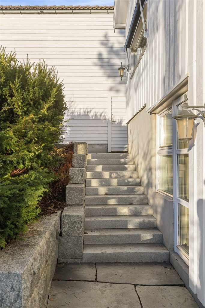 Tomt i flere plan opparbeidet med asfaltert innkjørsel, betong- og natursteinstrapper, samt støttemur i naturstein. I tillegg finnes plenarealer og variert beplantning.