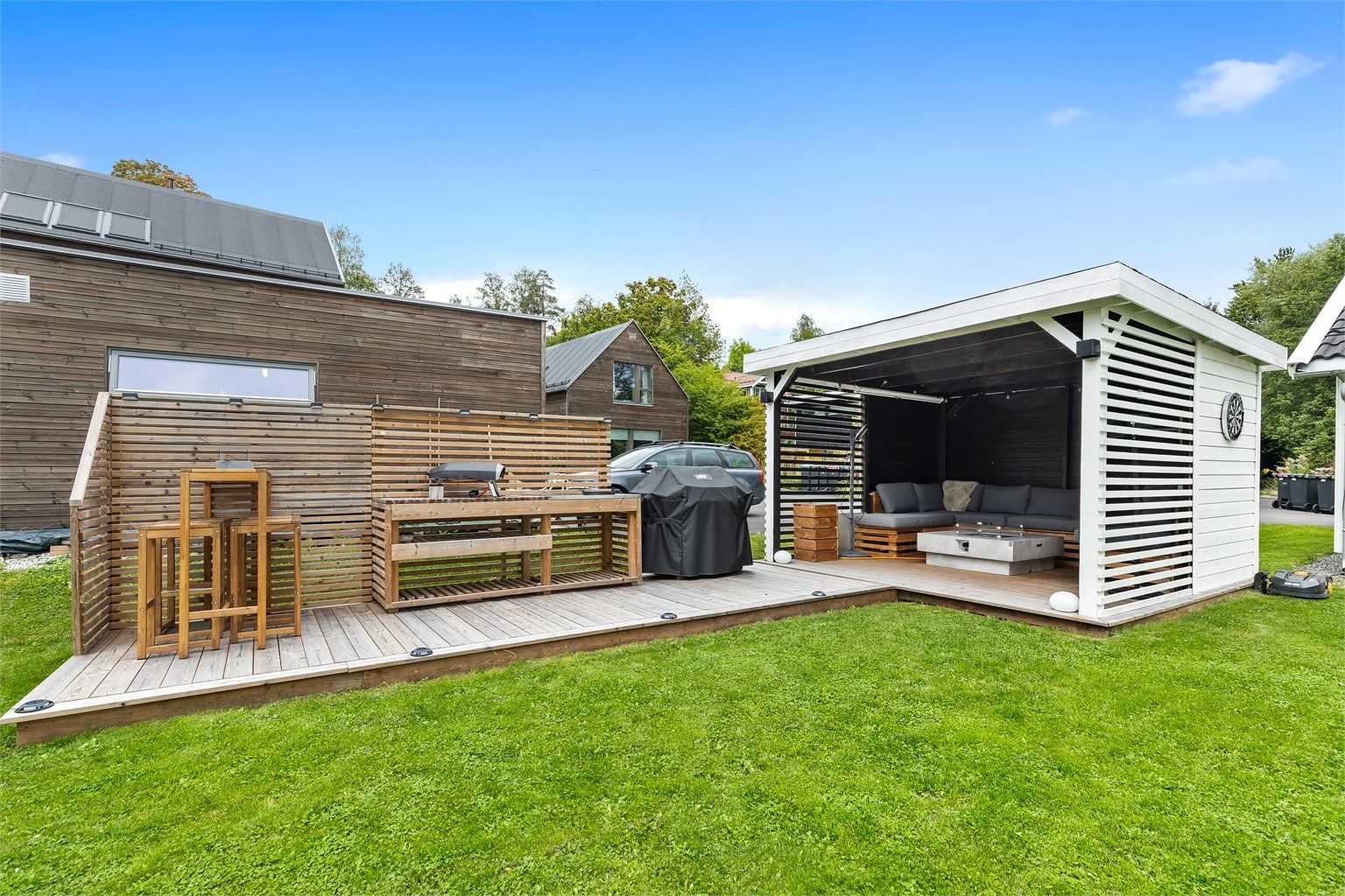 Platting med pergola, utekjøkken og gasspeis.
