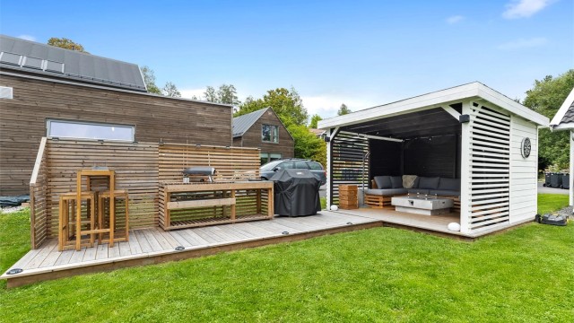 Platting med pergola, utekjøkken og gasspeis.