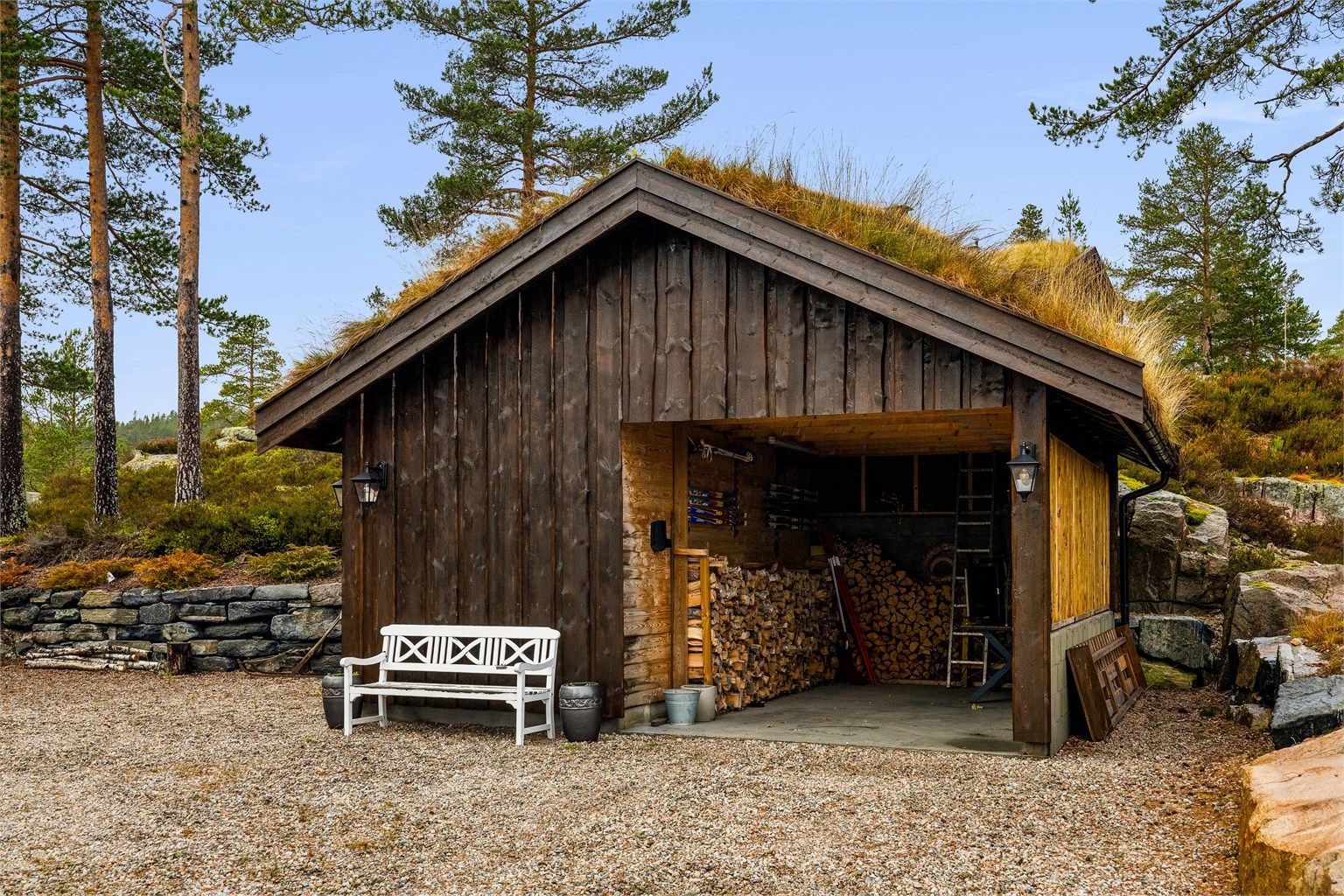 Carporten rommer både bil og ved. Ved siden av er det bod og et lite hobbyrom.