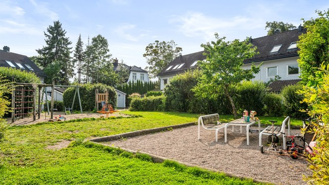 Bilfritt og grønt tun på midten av rekkehusene i borettslaget med plenarealer, lekestativer m.m.