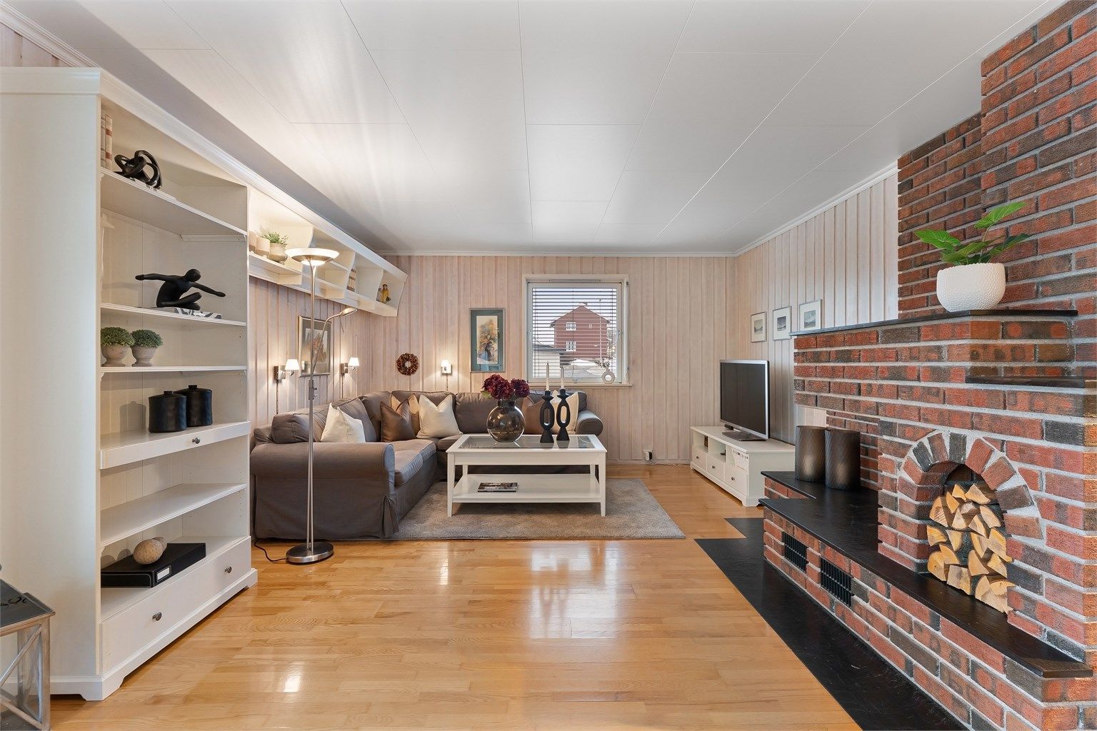 Stuen har god plass til en stor sofagruppe og er innredet med malt panel og takplater.