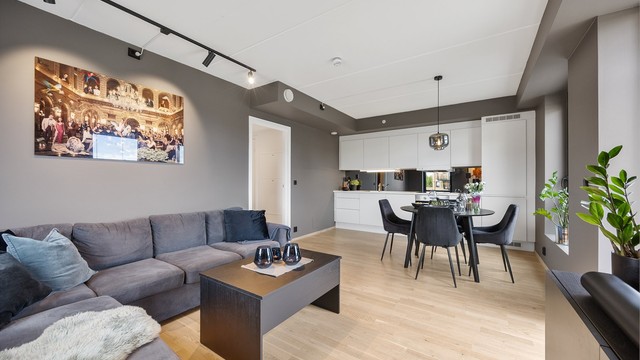 Stuen har god plass til hjørnesofa og bord, med åpen forbindelse til kjøkkenet.