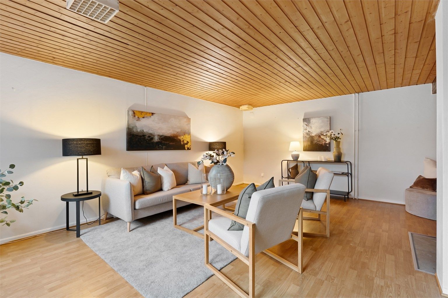 Stuen i underetasjen har panel i himlingen og en åpen peis som bidrar til en hyggelig atmosfære (ikke bruksendret/omsøkt)