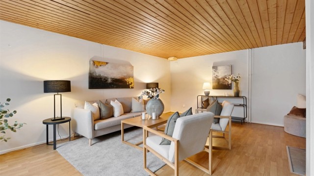 Stuen i underetasjen har panel i himlingen og en åpen peis som bidrar til en hyggelig atmosfære (ikke bruksendret/omsøkt)