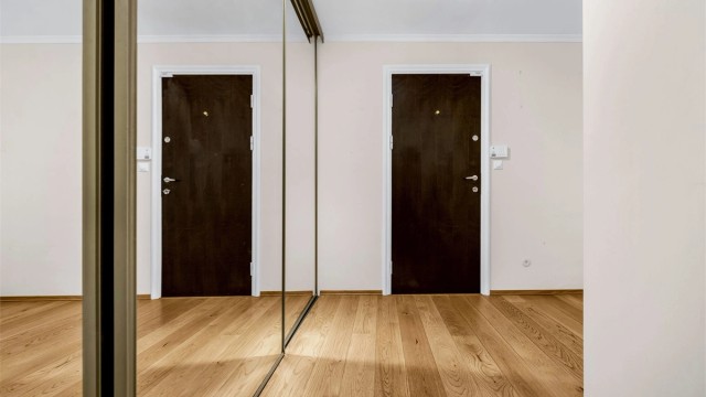 Romslig entre/hall med god plass for skooppbevaring og klesavheng i skyvedørsgarderobe med speilfronter.