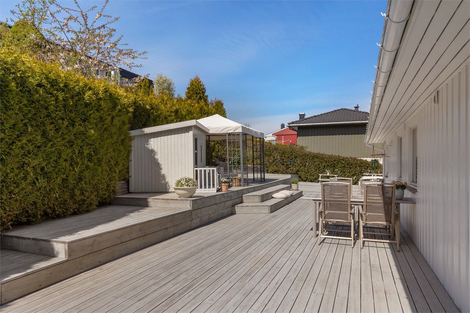 Hovedterrassen er omkranset av hekk mot nabo og har levegg mot gårdsplassen.