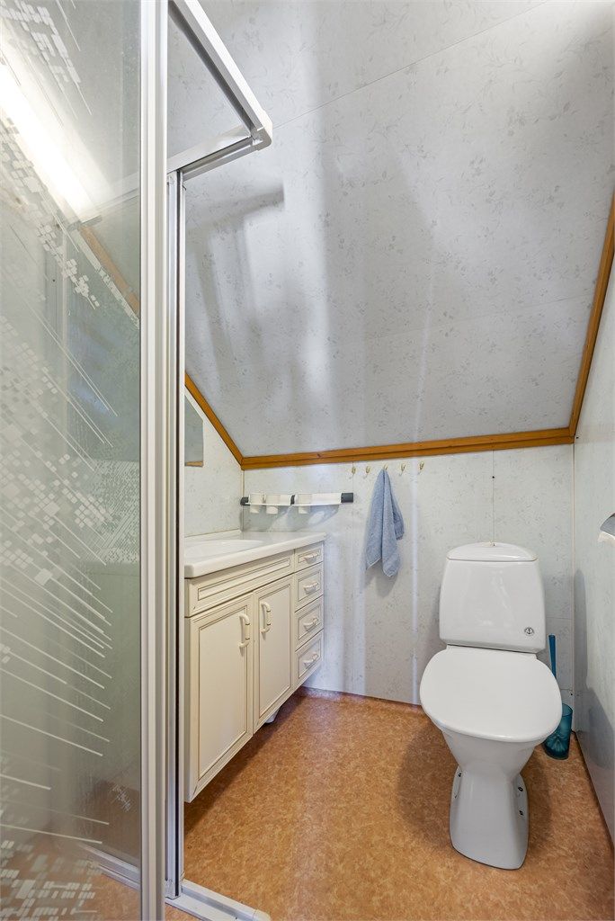 Badet på loftet har dusjnisje, gulvstående toalett og baderomsplater på veggene.