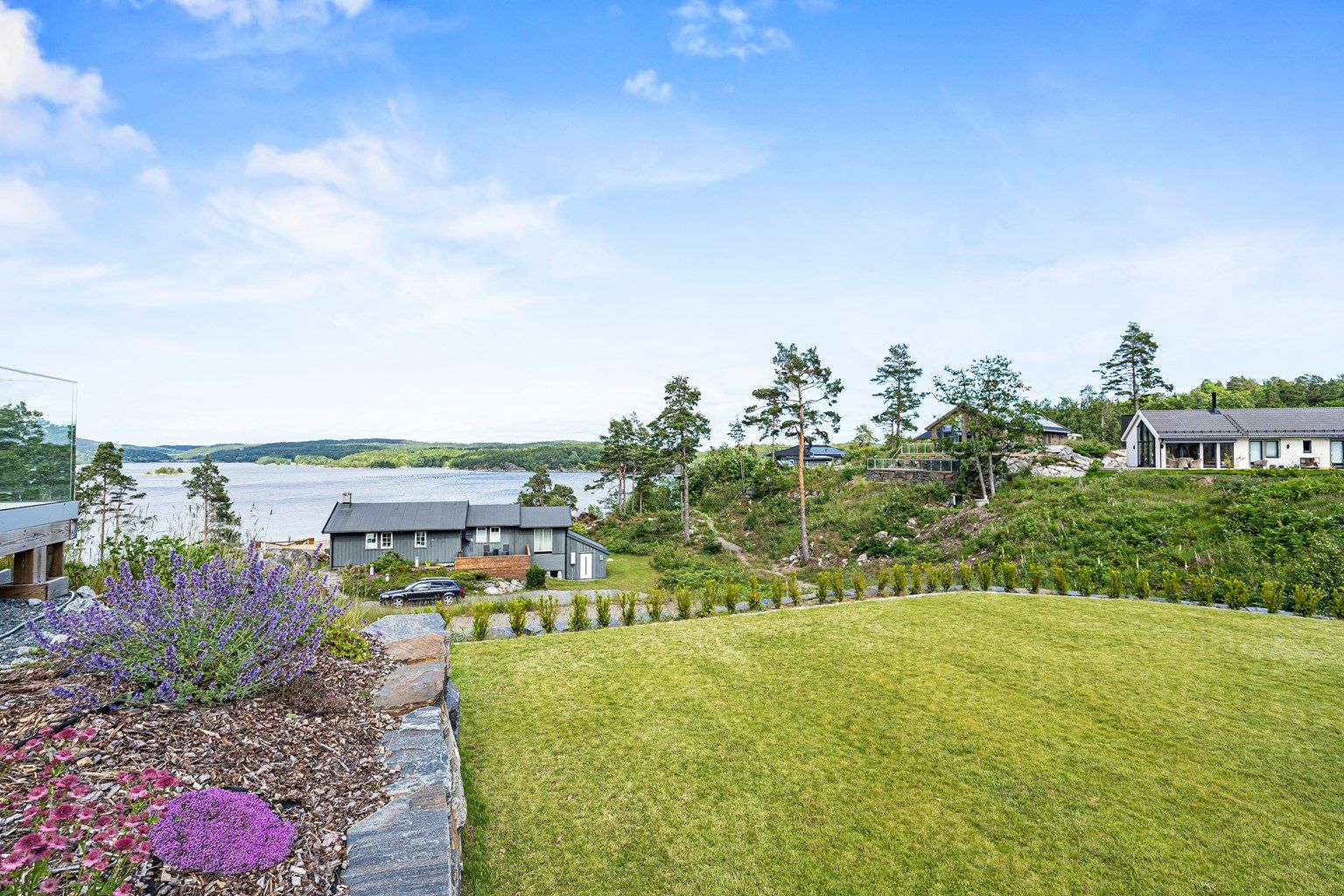 Pent opparbeidet tomt med hekk, plen. Stor terrasse.