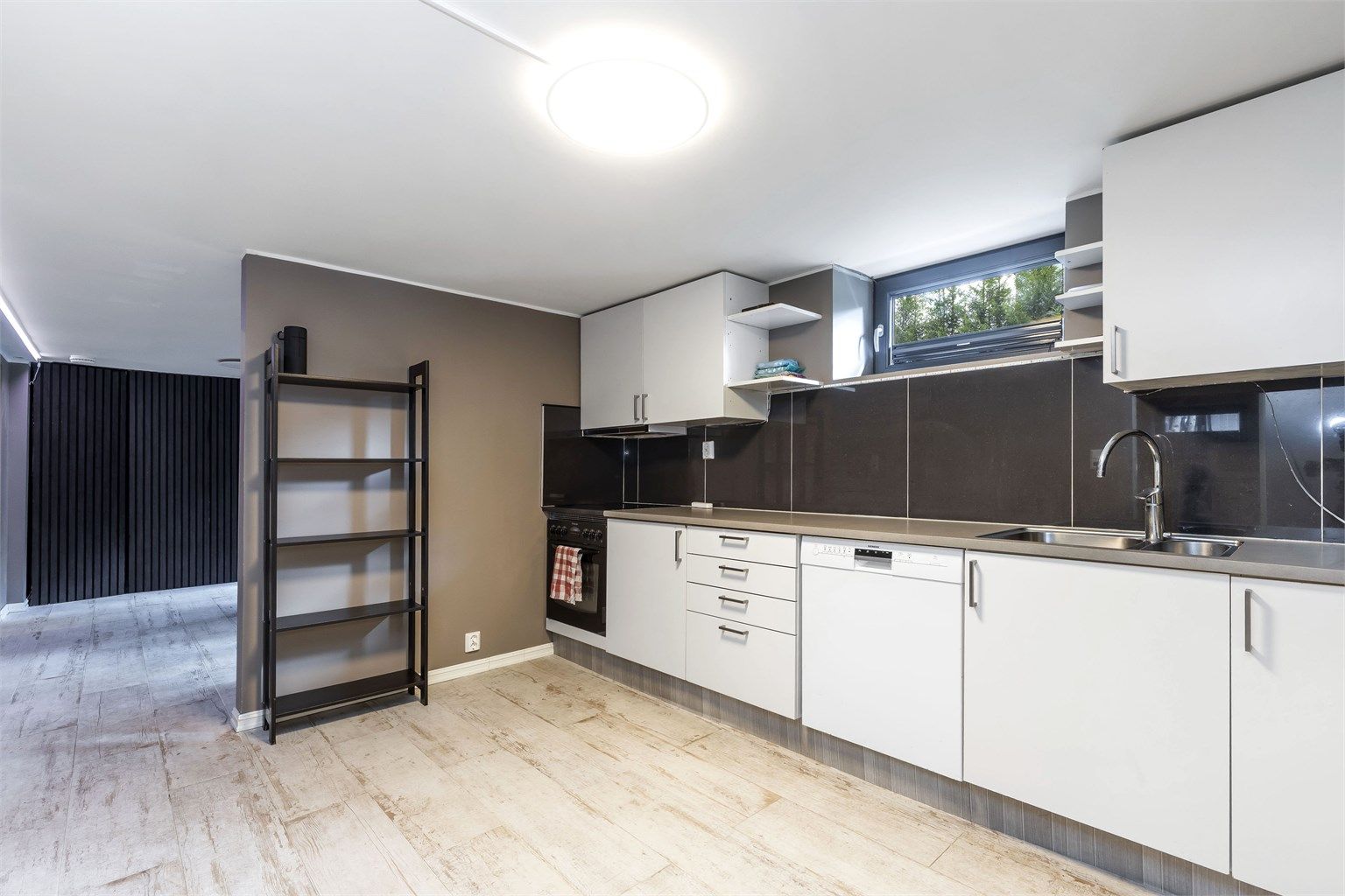 Kjelleren er innredet med tilknytting til leilighet i 1. etasje. Det gjøres oppmerksom på at plantegning for kjeller ikke samsvarer med ferdigattest som foreligger. Der det i dag er innredet kjøkken/entrè er ferdigattest godkjent som gang og 2 boder.