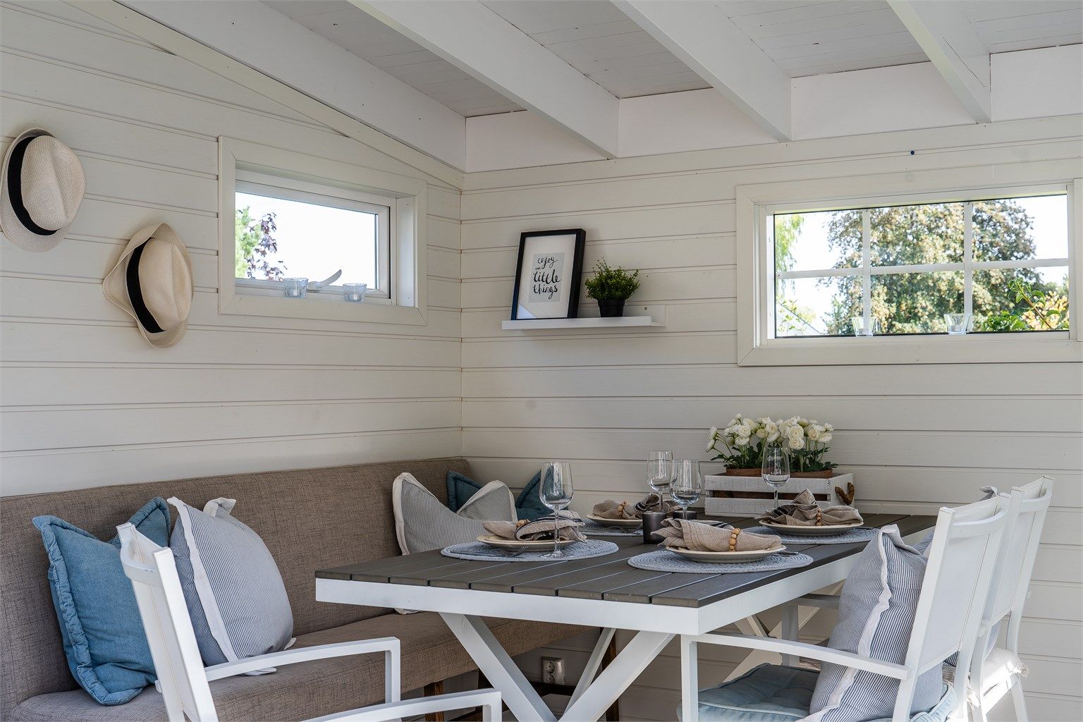 Frittstående utestue innredet med langbord og sittebenk for hyggelige sommerkvelder.